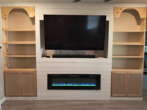 Living room setup featuring a wall-mounted TV, electric fireplace, and built-in shelves.
